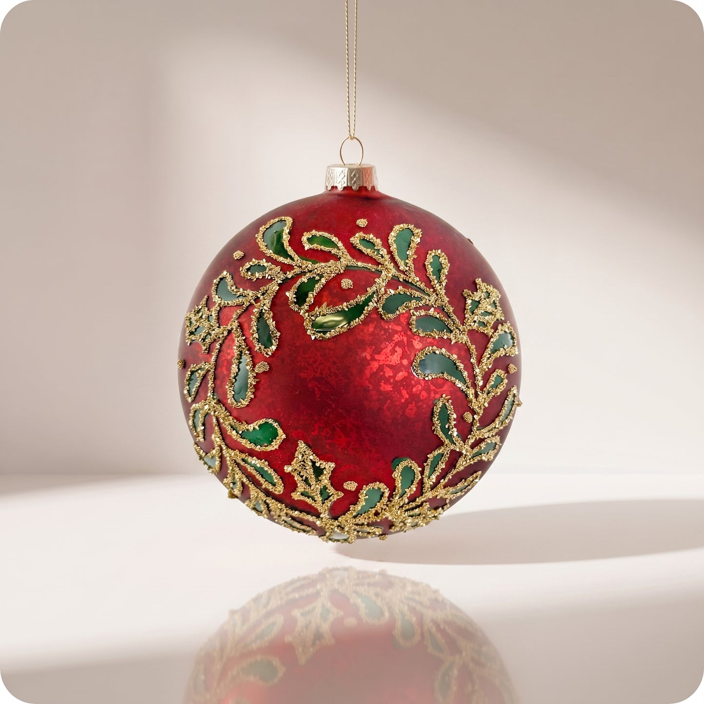 Esfera de cristal rojo con hojas verdes y brillos dorados 12 cm
