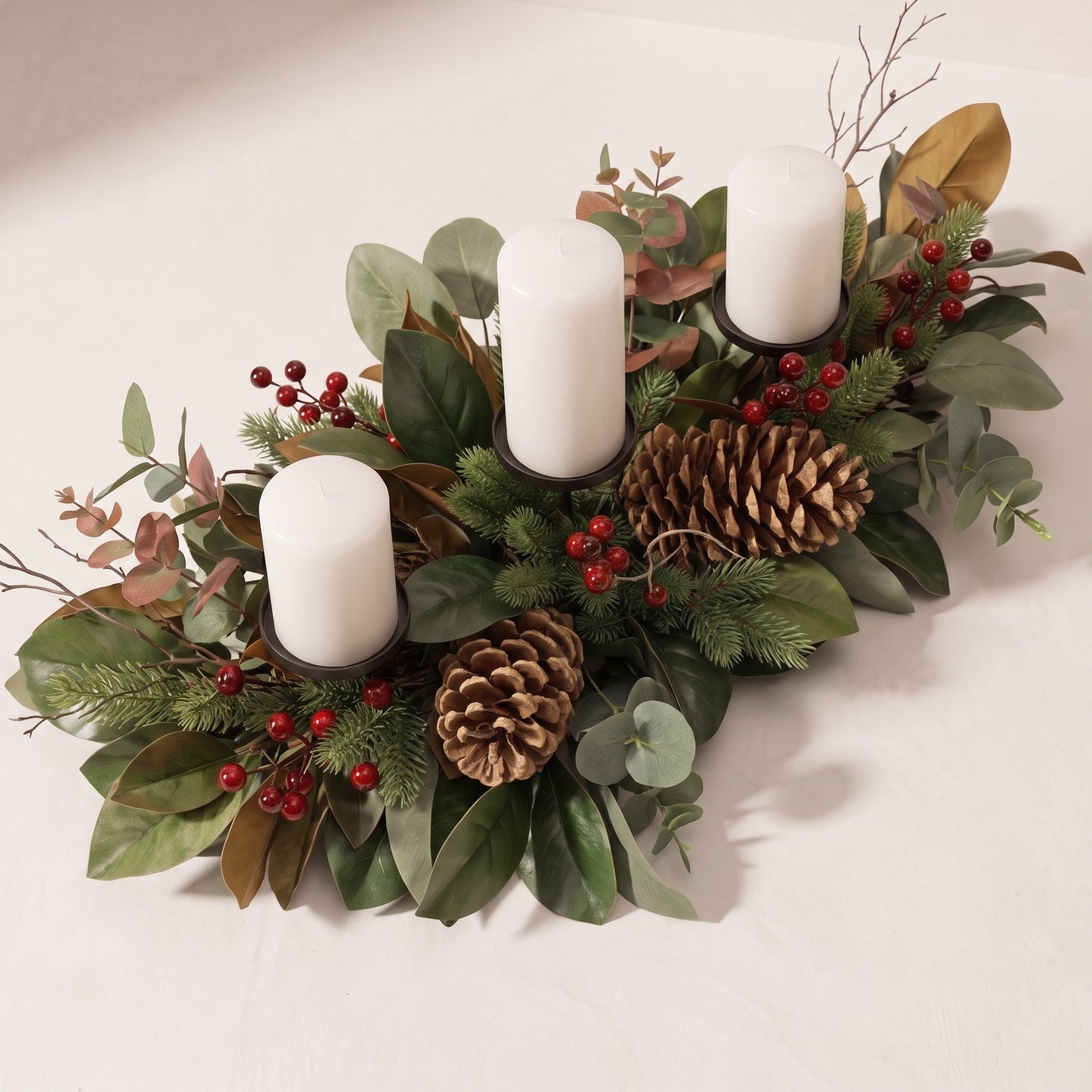 Centro de mesa con piñas, hojas de magnolia y porta velas